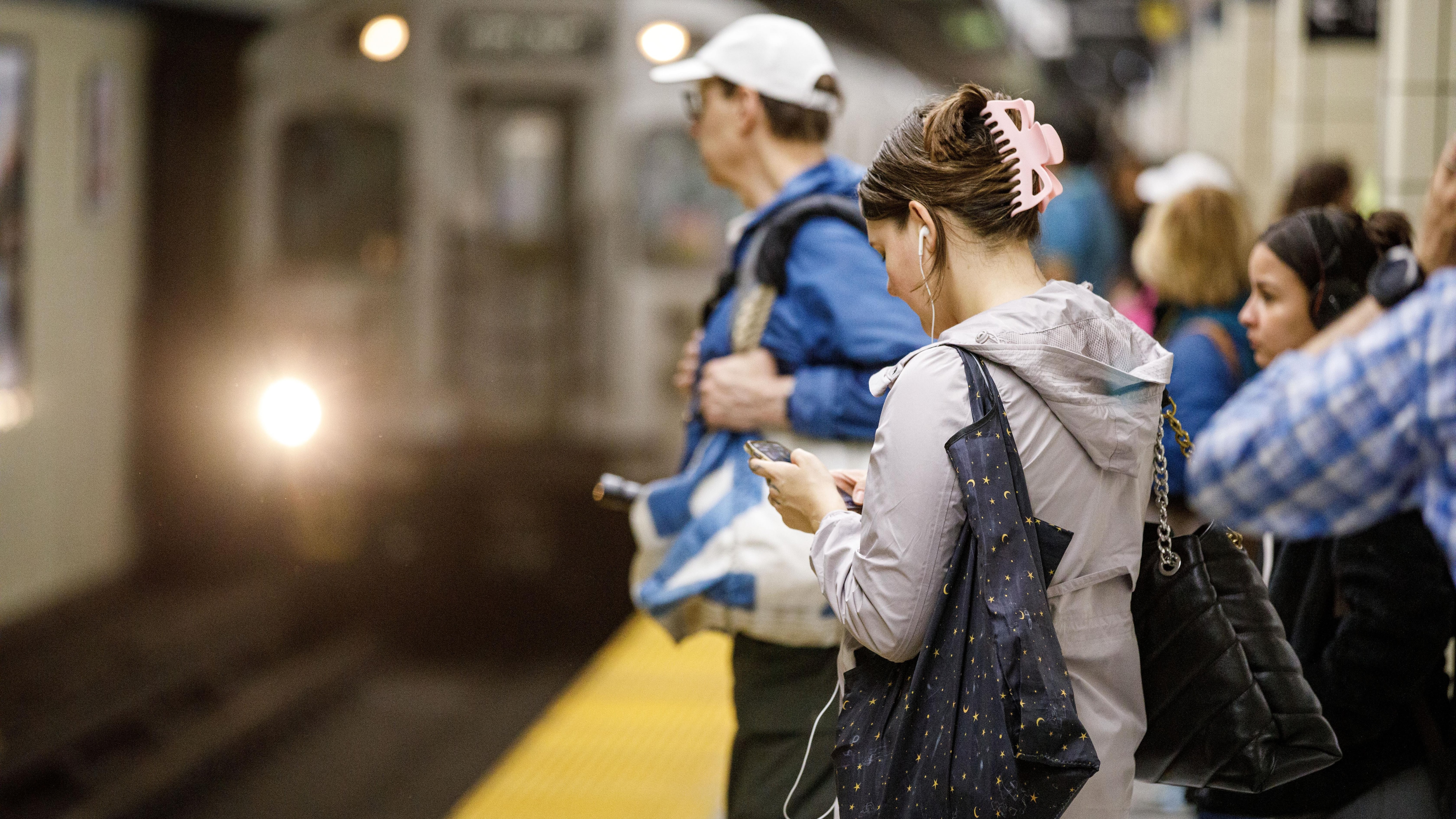 Des passagers en attente d'une rame à la station Yonge du métro de Toronto consulte leurs téléphones.